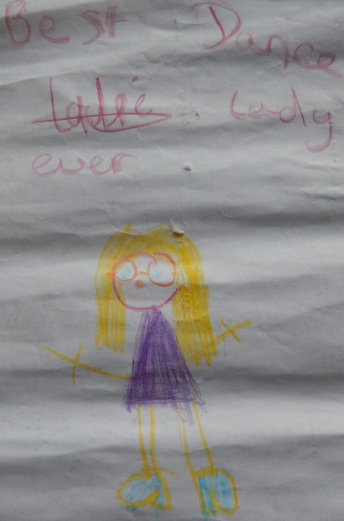 Child's drawing of a lady with blonde hair and glasses with the text 'best dance lady ever'